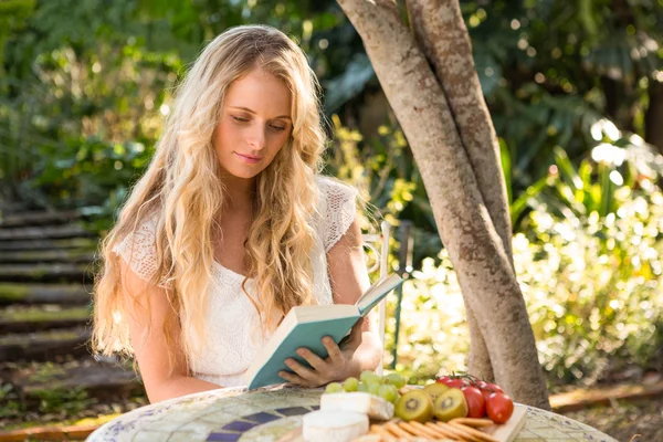 Blonde ontspannen en lezen met voedsel — Stockfoto