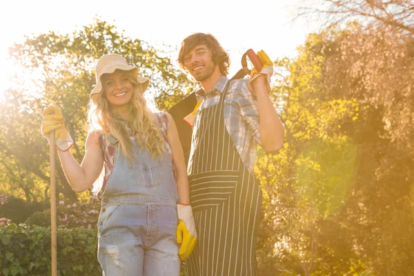 Pareja en el jardín sosteniendo un rastrillo — Foto de Stock