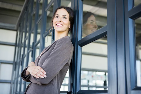 Businesswoman leaning on office door — Stock Photo, Image