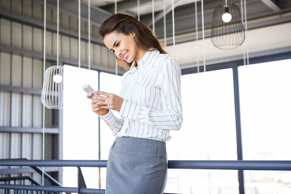 Zakenvrouw met mobiele telefoon op kantoor — Stockfoto