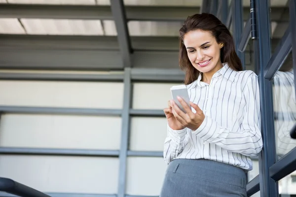 Femme d'affaires utilisant le téléphone mobile penchant — Photo