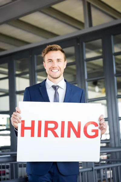 Businessman holding a hiring signboard — Stock Photo, Image