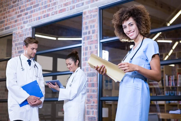 Médecin vérifiant un fichier près de la bibliothèque — Photo