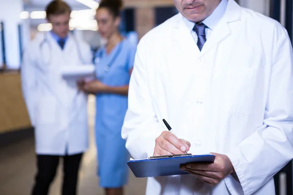 Male doctor writing on clipboard — Stock Photo, Image