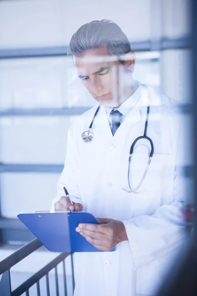 Doctor masculino escribiendo en portapapeles — Foto de Stock