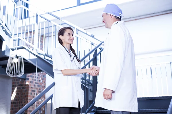 Doctors shaking hands on staircase — Stock Photo, Image