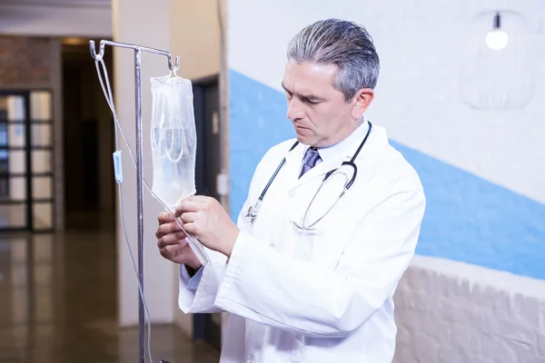 Médico verificando um gotejamento de soro fisiológico — Fotografia de Stock