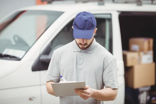Delivery man writing on clipboard — Stock Photo, Image