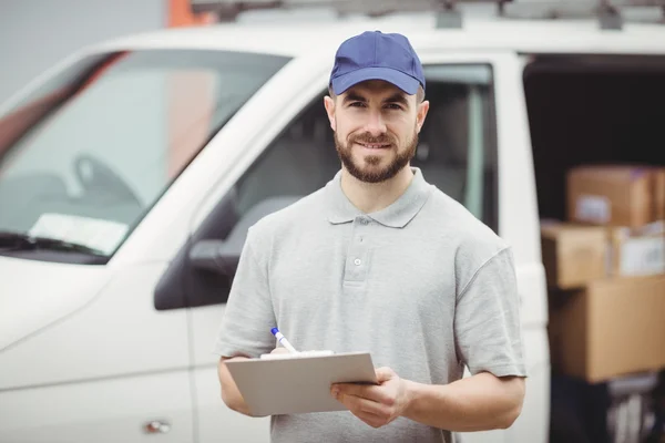 Delivery man writing on clipboard — Stock Photo, Image