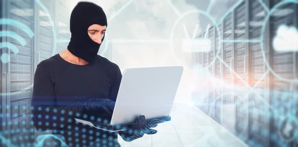 Burglar with balaclava hacking a laptop — Stock Photo, Image