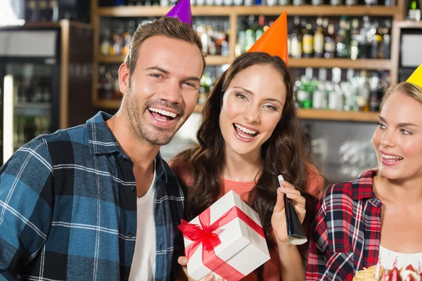 Vrienden met feestmutsen camera kijken — Stockfoto