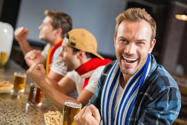 Man die op de camera, terwijl andere mannen voor het spel juichen — Stockfoto