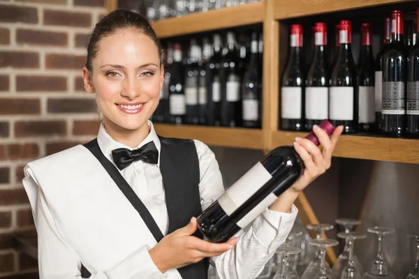 Barmaid tenant une bouteille de vin — Photo