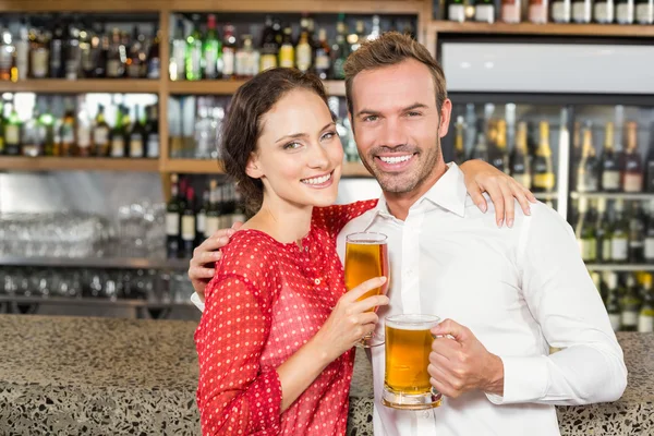 Couple smiling at camera and holding beers — Stock Photo, Image