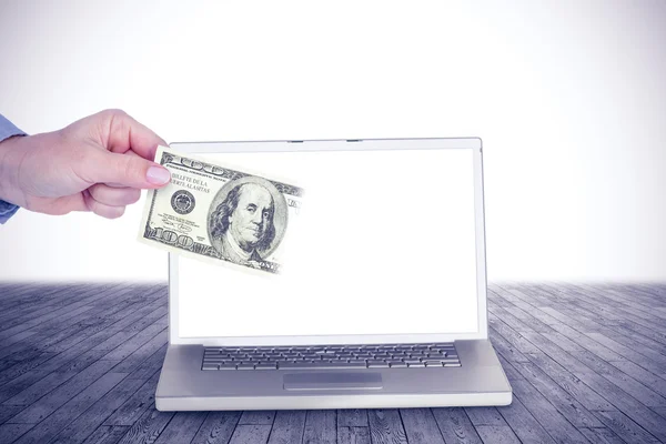 Hand met geld tegen laptop op tafel — Stockfoto