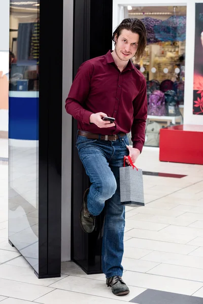 Man houdt een boodschappentassen en met behulp van een mobiele telefoon — Stockfoto
