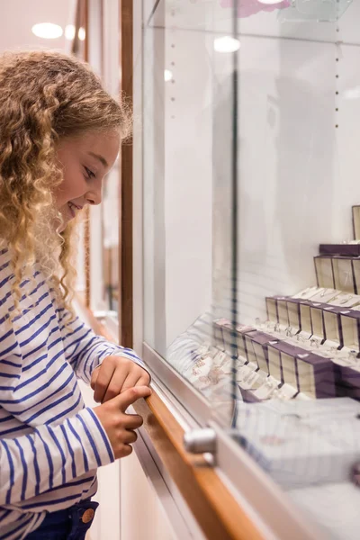 Gelukkig meisje op zoek naar sieraden display — Stockfoto