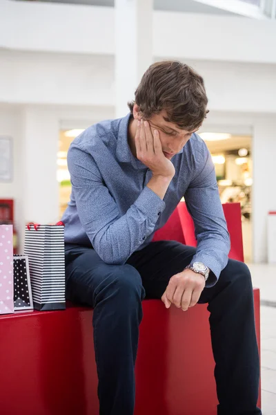 Hombre cansado sentado en el centro comercial — Foto de Stock