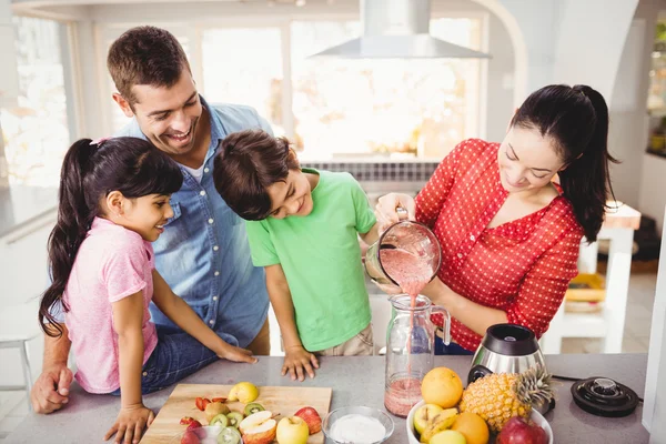 Familj med mor hälla fruktjuice — Stockfoto