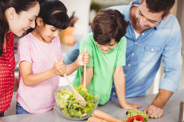 Leende flicka förbereda sallad med familj — Stockfoto