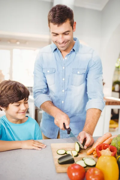 Man chopping vegetable with son — Stock Photo, Image