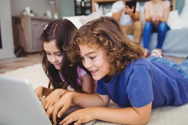 Irmãos usando laptop em casa — Fotografia de Stock