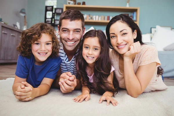 Feliz família deitada no tapete — Fotografia de Stock