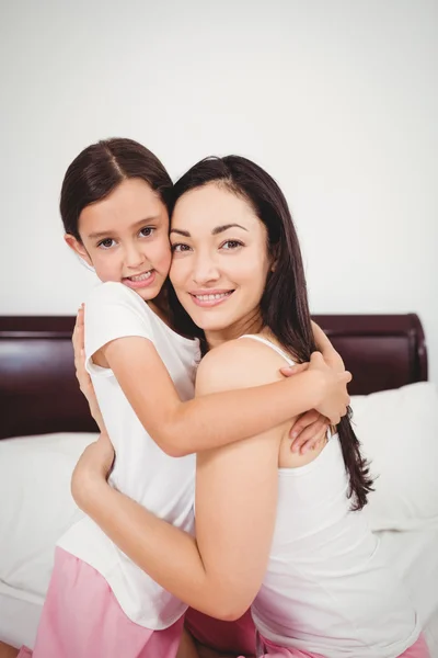 Mother hugging daughter on bed — Stock Photo, Image