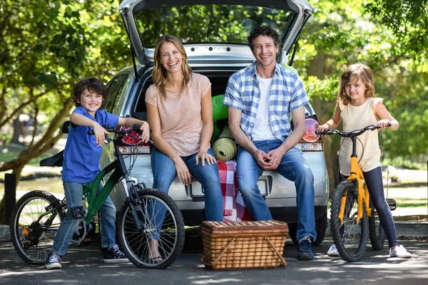 Família sorridente na frente de um carro — Fotografia de Stock
