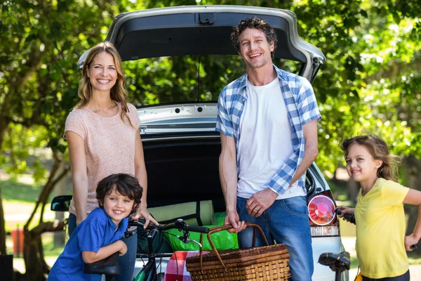 Familia sonriente frente a un coche — Foto de Stock