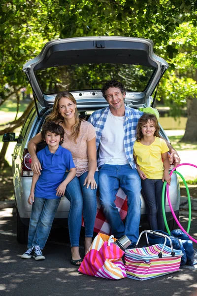 Família sorridente sentada na sala de bagagens — Fotografia de Stock