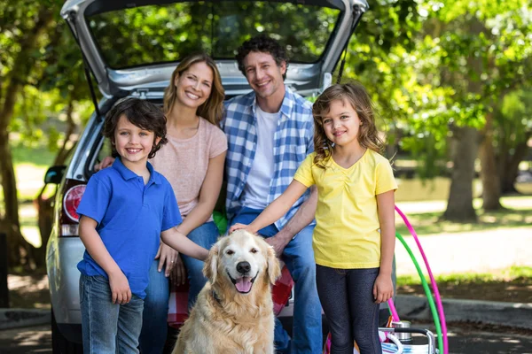 Família sorridente na frente de um carro — Fotografia de Stock