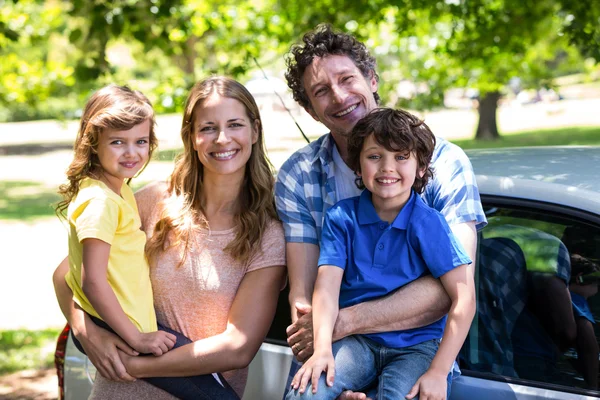 Famille souriante devant une voiture — Photo