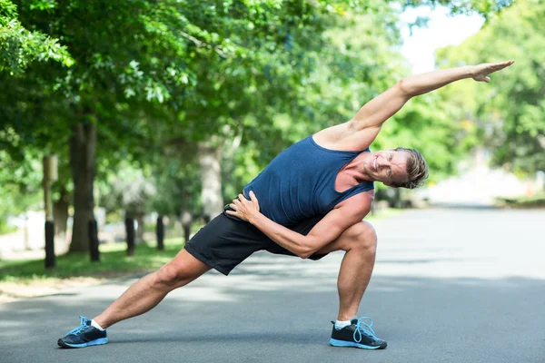 Sportsman stretching in park — Stock Photo, Image