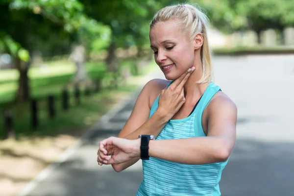 Sportvrouw controleren haar hartslag horloge — Stockfoto