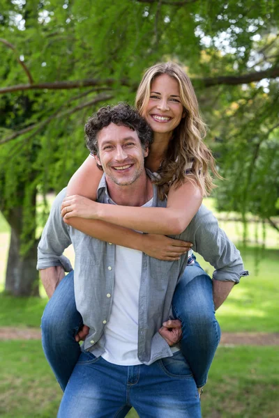 Husband giving a piggy-back to his wife — Stock Photo, Image