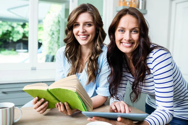 Amigos do sexo feminino com livro e tablet digital — Fotografia de Stock