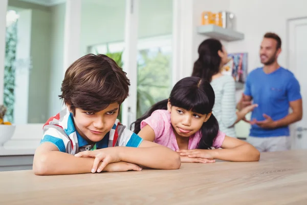 I bambini che fanno facce mentre siedono a tavola — Foto Stock