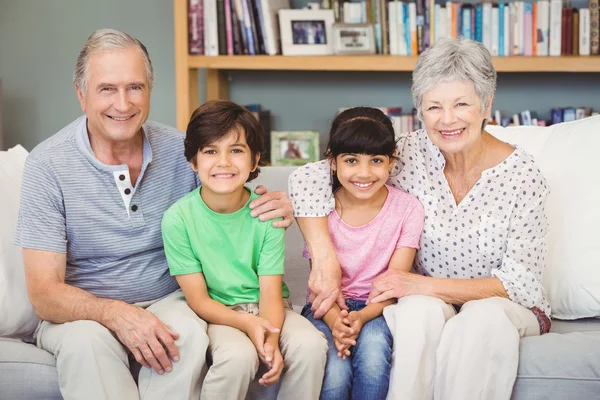 Grandchildren with grandparents sitting at home — Stock Photo, Image