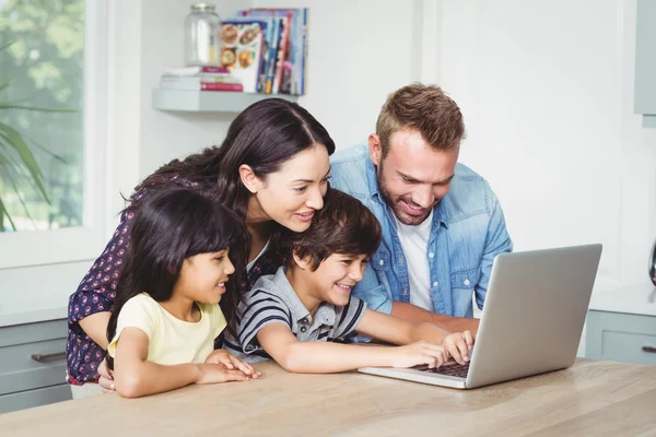 Família sorrindo usando laptop — Fotografia de Stock