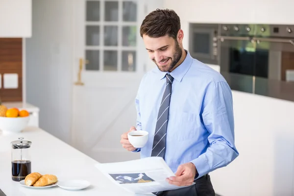 Empresario leyendo periódico mientras bebe café — Foto de Stock