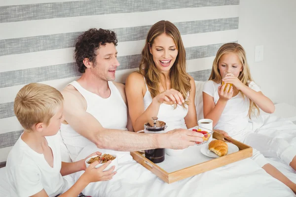 Family enjoying breakfast on bed — Stock Photo, Image