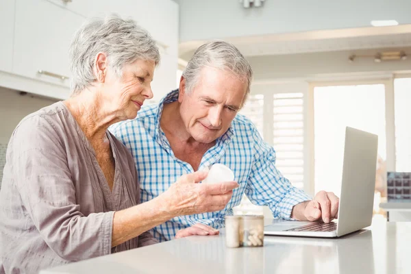 Vrouw met pillen die man met laptop — Stockfoto