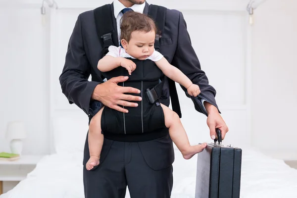 Padre llevando al bebé mientras sostiene el maletín — Foto de Stock