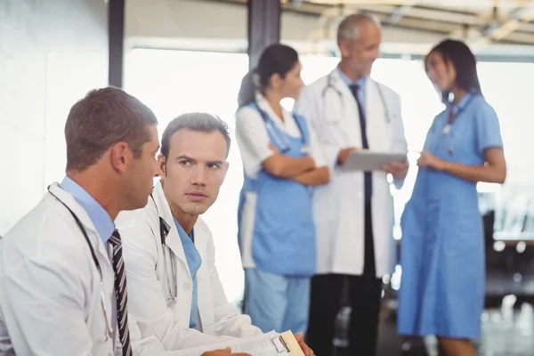 Two doctors with clipboard and discussing — Stock Photo, Image