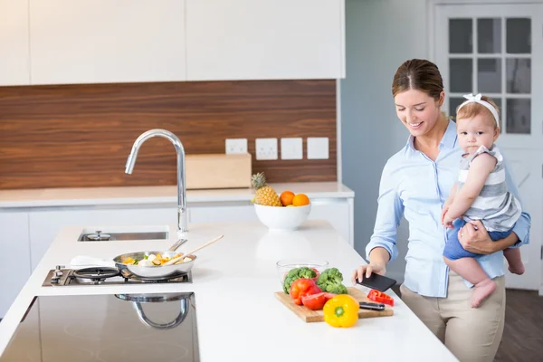 Mujer llevando hija por mostrador de cocina — Foto de Stock