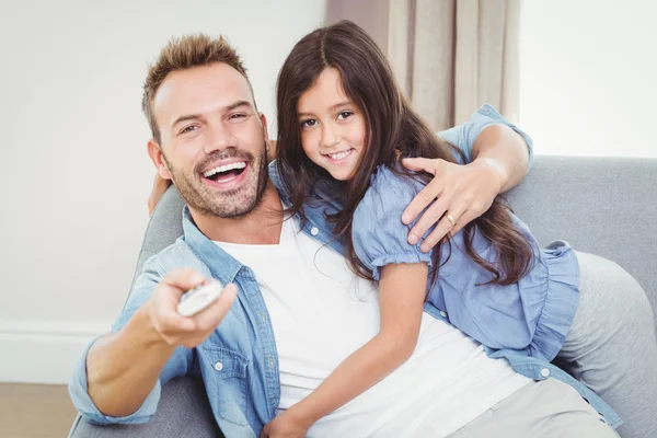 Figlia sorridente che abbraccia il padre sul divano — Foto Stock
