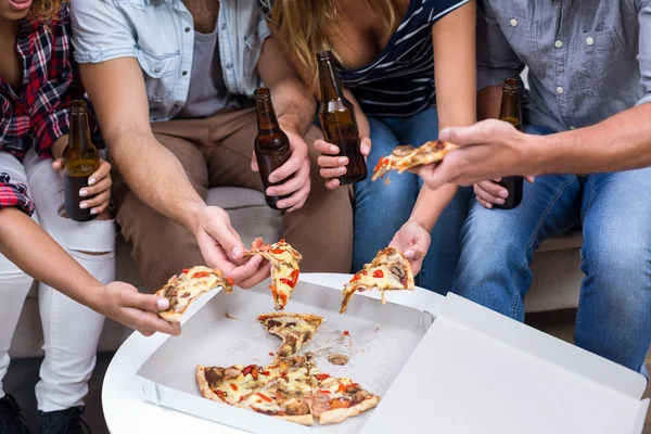 Amici che tengono la birra mentre mangiano pizza — Foto Stock