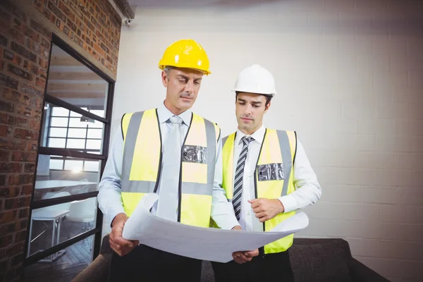 Arquitetos discutindo enquanto segurando o plano — Fotografia de Stock