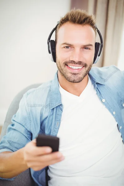 Homem ouvindo música enquanto segurando móvel — Fotografia de Stock